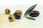 Olives with leaves and olive oil on a plate