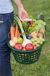 A woman carrying a basket of fruit and vegetables