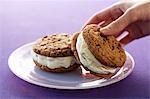Hand Grabbing a Cookie Ice Cream Sandwich From a Plate