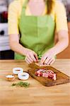 Woman Adding Fresh Herbs to Season a Steak