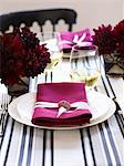 A place setting with a white plate and a pink napkin