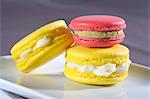 Macarons jaunes avec macaron vanille de crème, rose avec crème de pistache