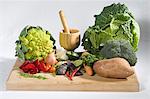 Vegetable still life with mortar and pestle with rose petals on a cutting board