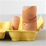 A stack of egg shells in a yellow egg box