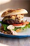 Schweizer Käse-Burger mit Pilzen, Tomaten, Zwiebeln und Salat auf SESAM Brötchen