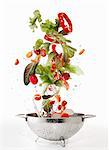 Salad ingredients being washed in a colander