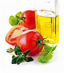 Tomatoes, a bottle of olive oil and fresh herbs (close-up)