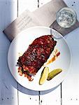 Spare ribs with gherkins and a glass of water (seen from above)