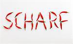 Das Wort 'SCHARF' ('Spicy' in deutscher Sprache) geschrieben in roten Chilischoten