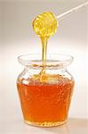 Honey drizzling off an acrylic spoon into a jar