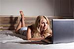 Femme utilisant un ordinateur portable sur le lit