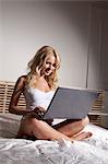 Woman using laptop on bed