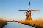 Windmill by river in rural landscape