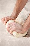 Chef kneading dough in kitchen