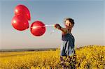 Girl carrying balloons in field