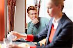 Man looking at a businesswoman having food in a restaurant