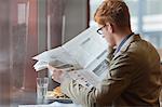 Homme assis dans un restaurant et d'un journal de lecture