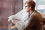 Man sitting in a restaurant and reading a newspaper