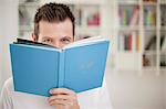 Portrait of a holding a book in front of his face