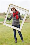 Portrait of a woman standing with a frame in a park