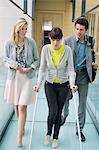 Disable woman walking with business executives in an office corridor