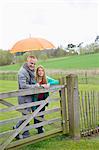 Homme debout avec sa fille dans une ferme avec un parapluie