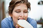 Close-up of a woman eating toast with cream spread on it