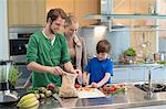 Parents en regardant leurs légumes de coupe des fils dans la cuisine