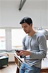 Man leaning against a pool table using a mobile phone