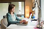 Jeune fille à l'aide d'un ordinateur portable à la maison