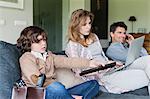 Family using electronic gadgets in a living room