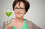 Woman looking at an hourglass and smiling