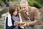 Man with his daughter holding a bird's nest in a park