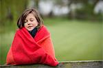 Girl wrapped in a blanket with her eyes closed in a farm