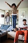 Naughty boy jumping on couch with his parents at home