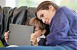 Femme regardant son fils à l'aide d'une tablette numérique