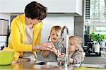 Elderly woman with her granddaughters washing in a kitchen