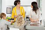 Two girls with her mother and grandmother discussing in a kitchen