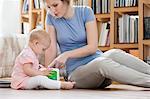 Woman sitting near her daughter playing with a toy