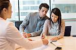 Couple signing documents with business executive