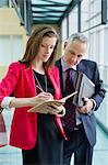 Business executives doing paperwork in an office corridor