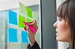 Businesswoman drawing heart shape on an adhesive note in an office