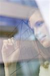 Businesswoman drawing a house on a glass surface