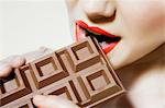 Young woman biting chocolate, close up