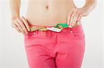 Young woman measuring waist with tape measure