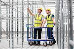 Two men in empty warehouse with trolley