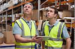 Men in warehouse using digital tablet