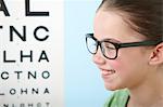 Girl wearing glasses with eye chart in background