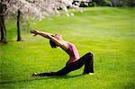 Woman in crescent moon yoga position in park