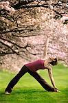 Woman in triangle yoga position near cherry tree